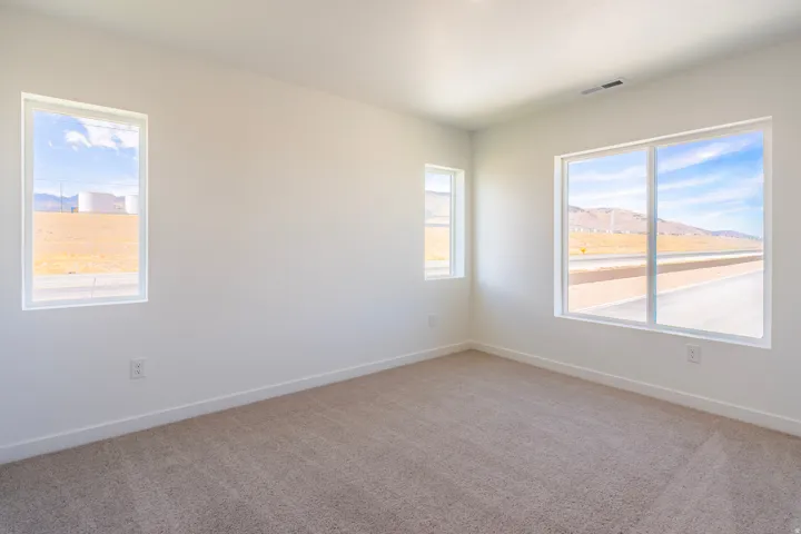 Spacious room with multiple windows, light-colored walls, and neutral carpet flooring