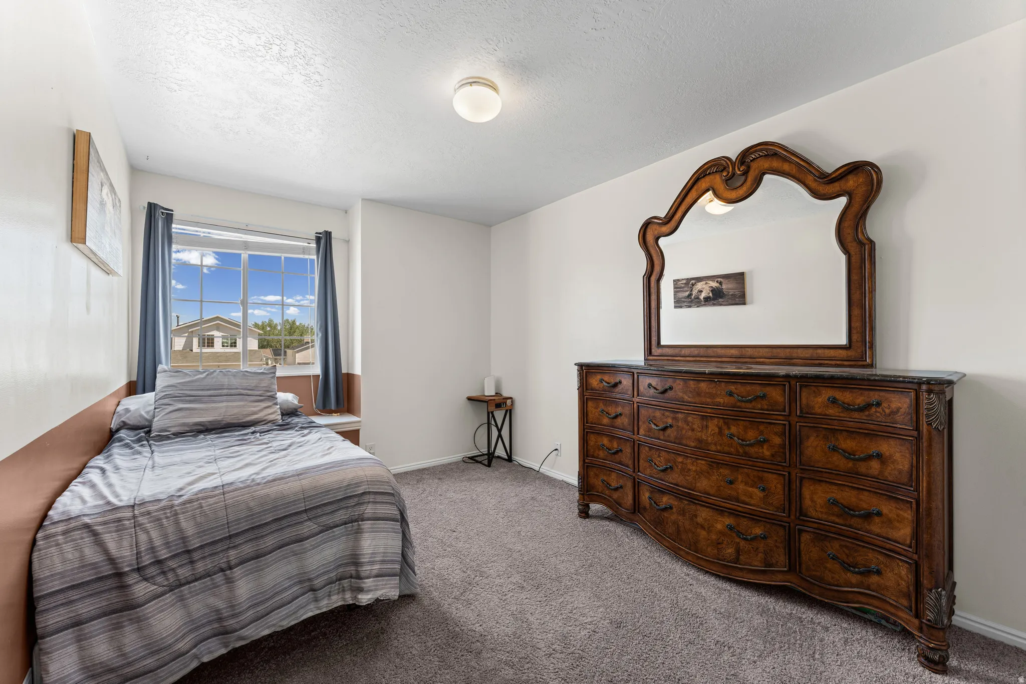 Carpeted room with a double-paned window, featuring a built-in window seat, a ceiling-mounted light fixture, and neutral wall tones