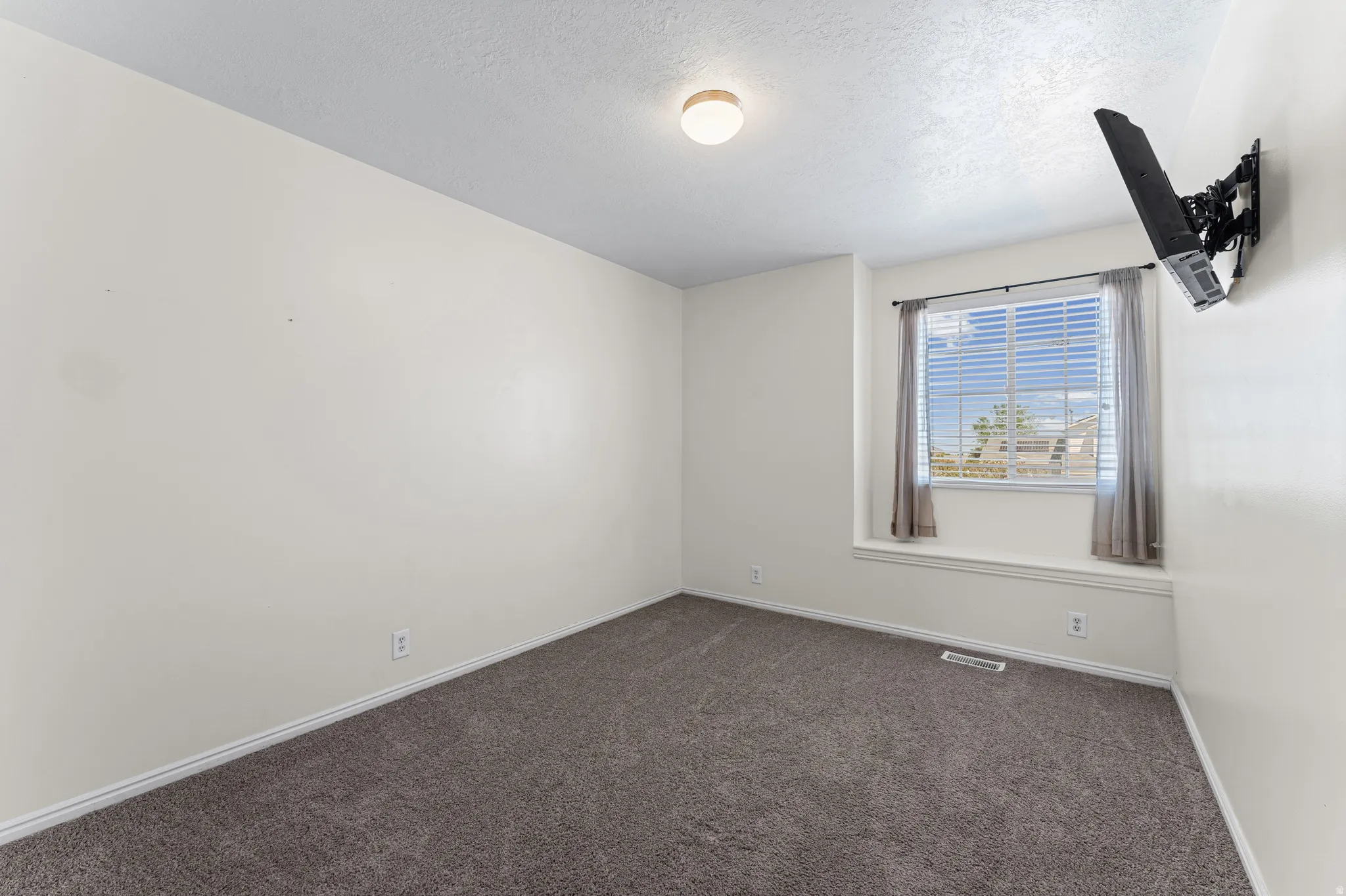 Room featuring light gray wall paint, dark gray carpeting, and white baseboards