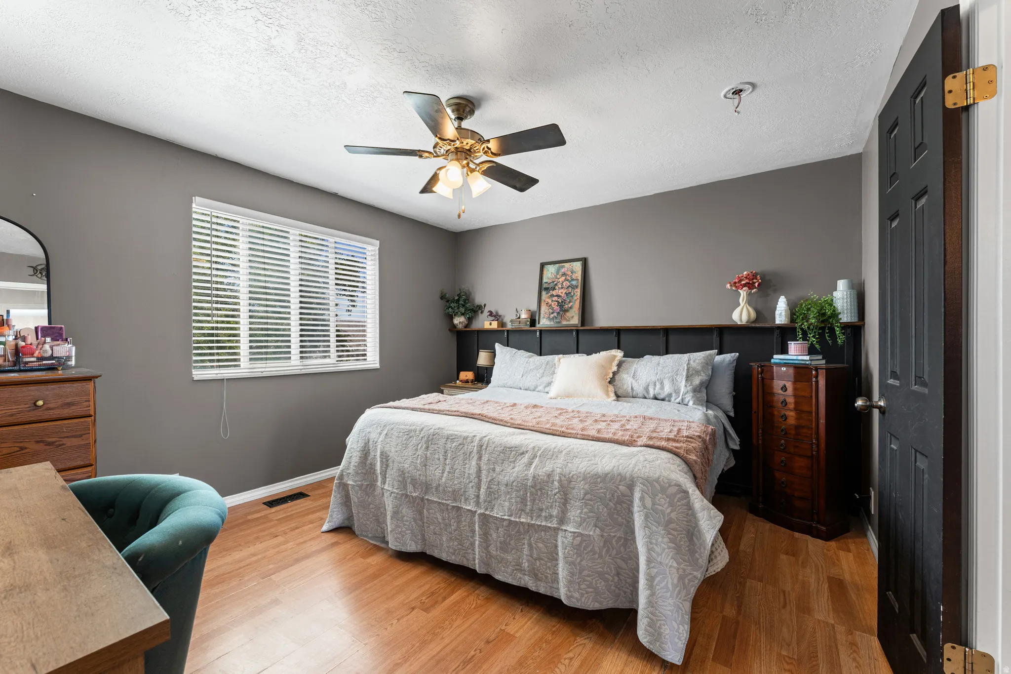Room featuring wood-finish flooring, a ceiling fan with integrated lighting, and a window with horizontal blinds