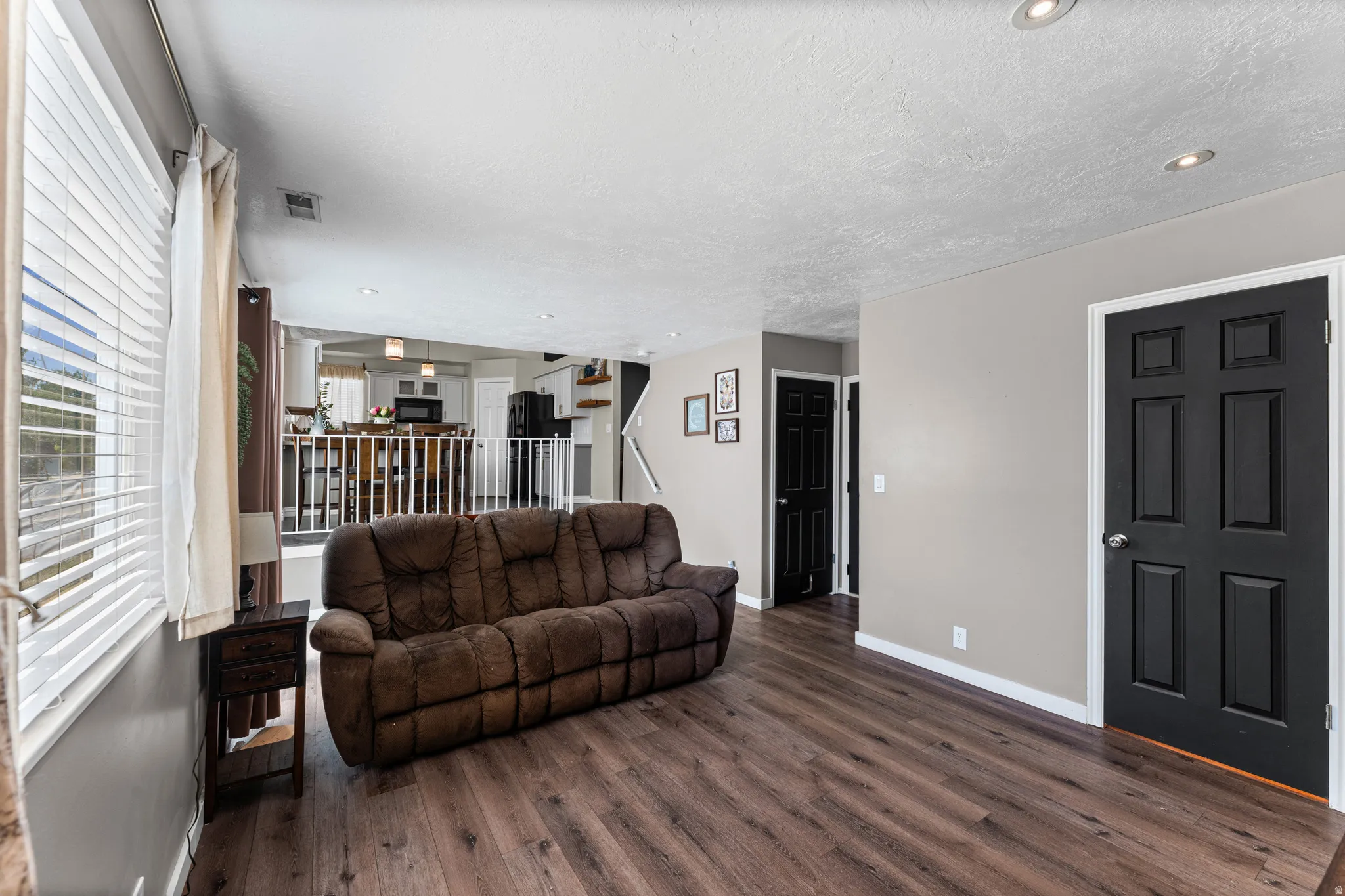 Open concept living area featuring wood-finish flooring, recessed lighting, and a white baluster railing