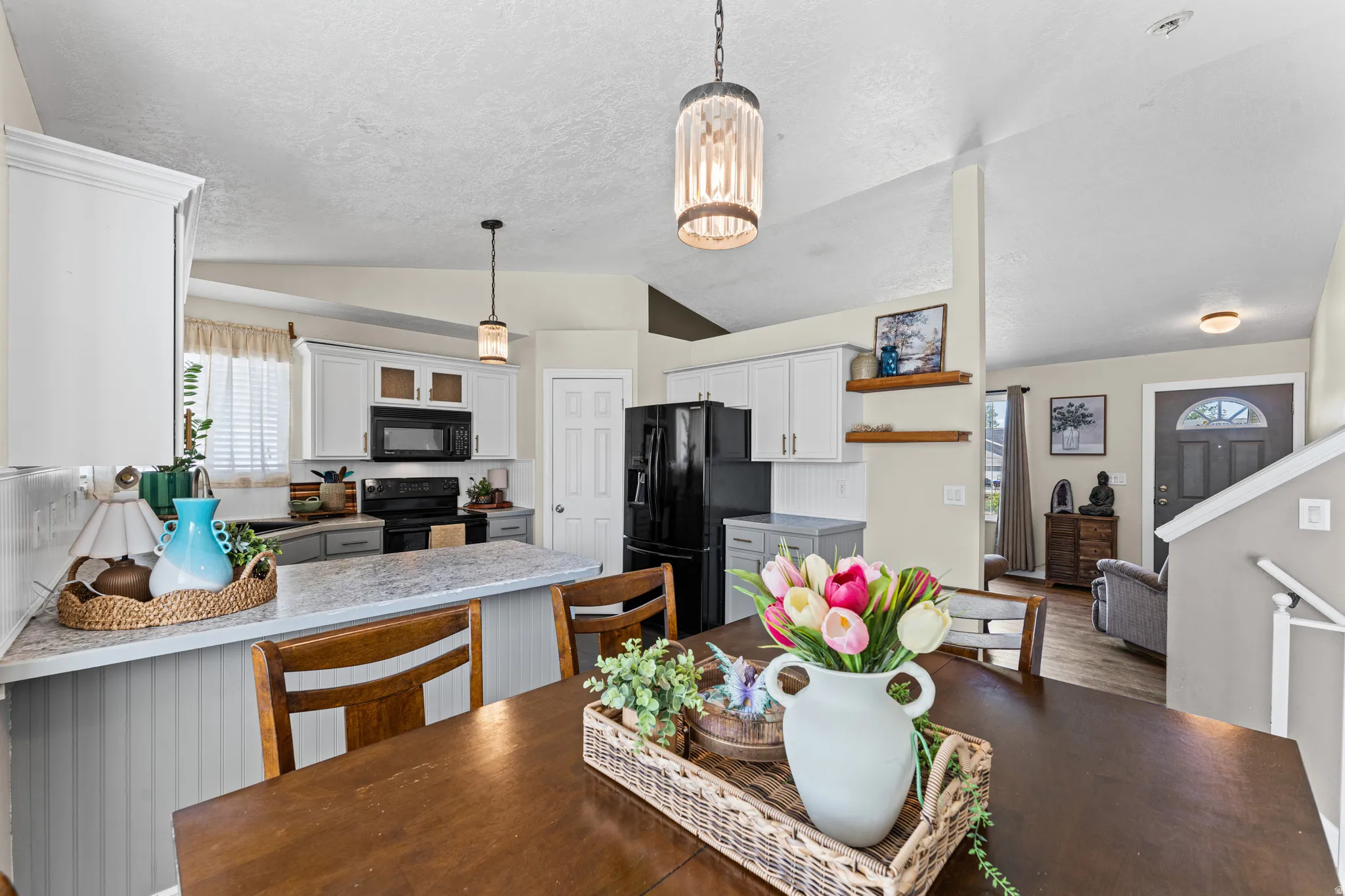 Open-concept kitchen and dining area featuring a kitchen island with a light-toned countertop, white upper cabinetry, and contrasting grey lower cabinetry