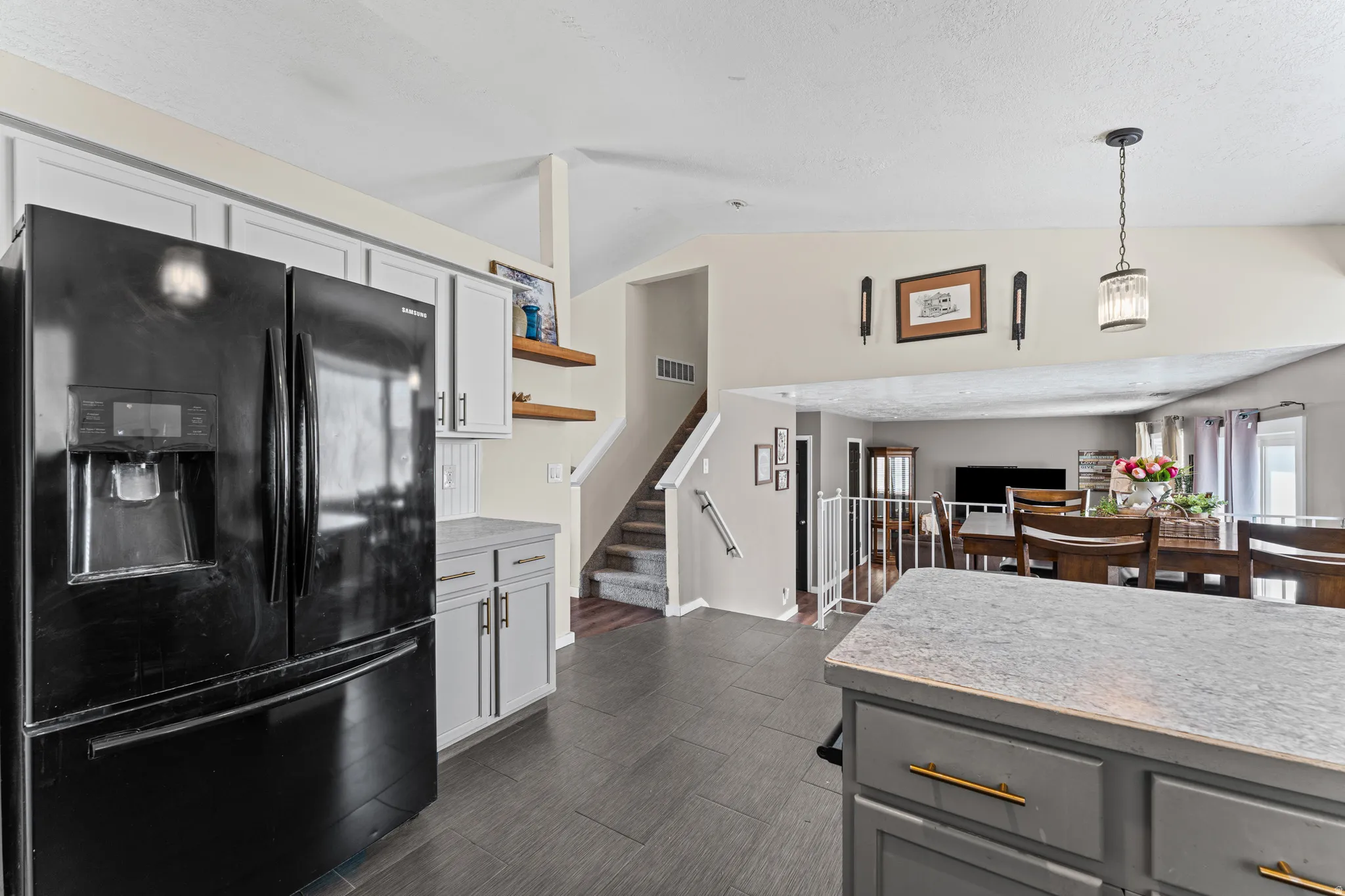 Kitchen featuring a black refrigerator, light gray perimeter cabinetry, and an island with gray countertops