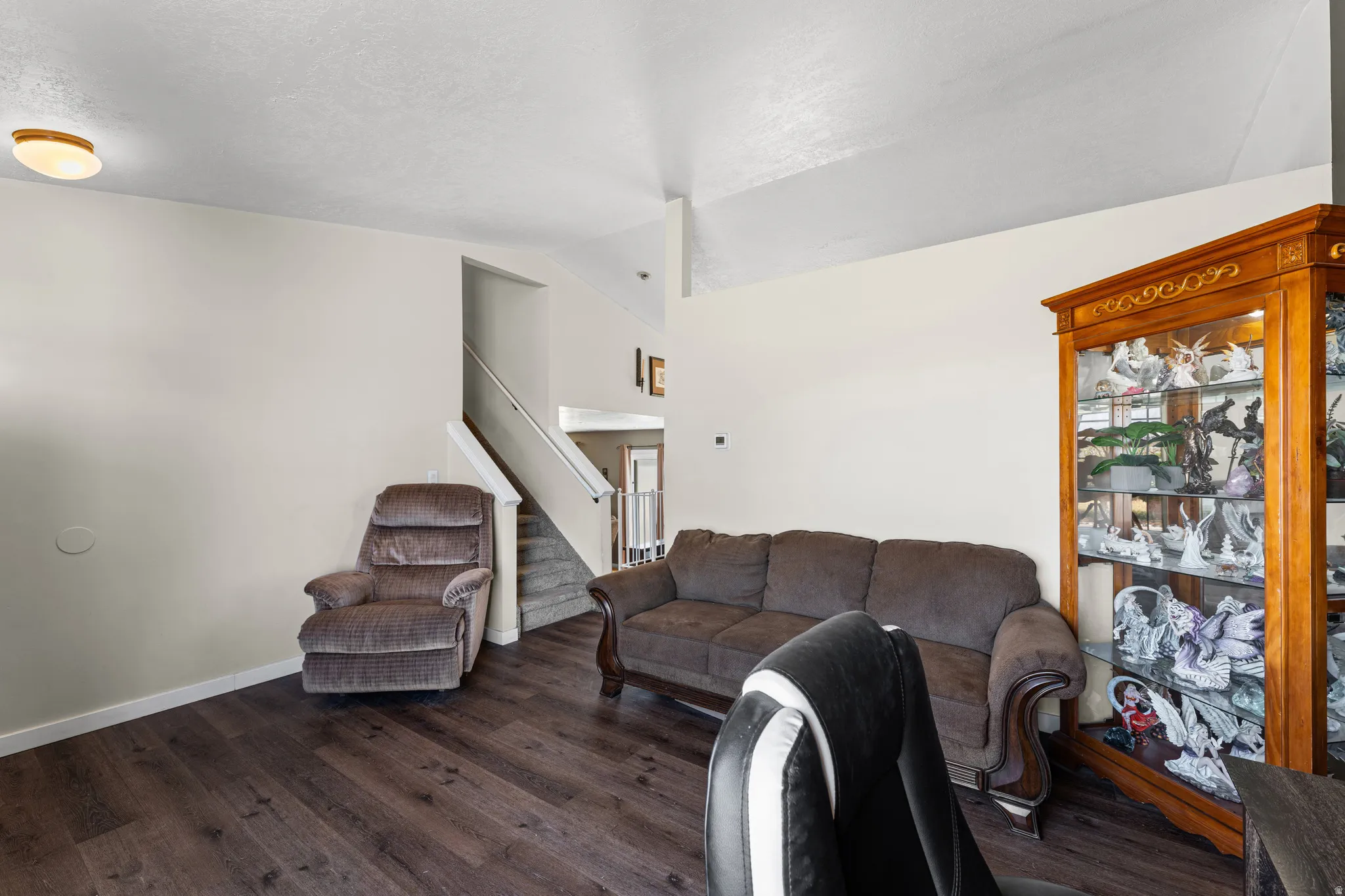 Spacious living area featuring wood-finish flooring, vaulted ceilings, and light neutral wall tones