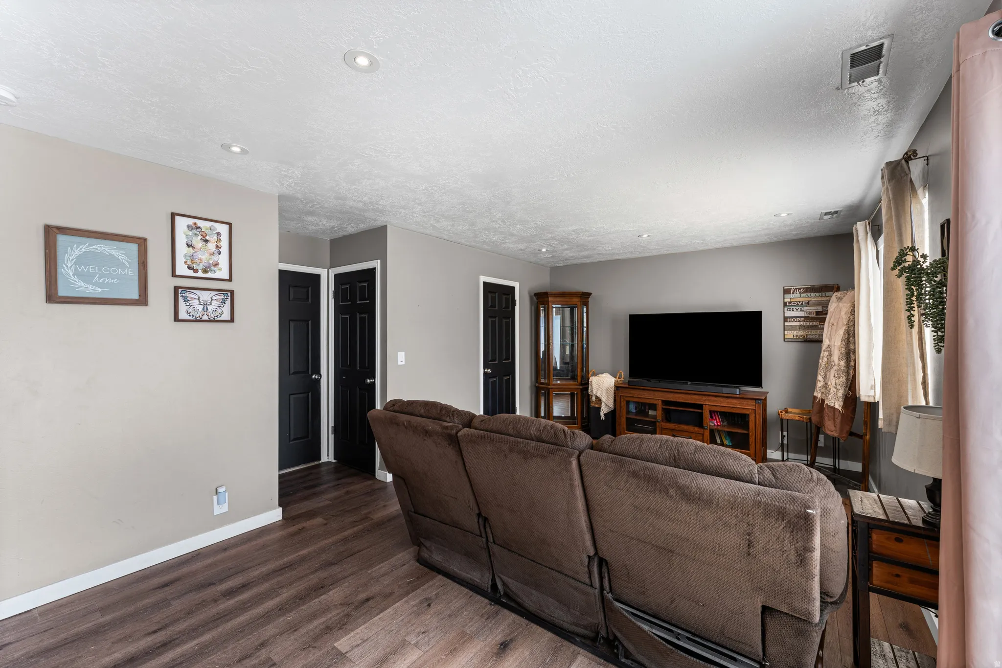 Spacious living area featuring wood-finish flooring, recessed ceiling lighting, and neutral wall tones