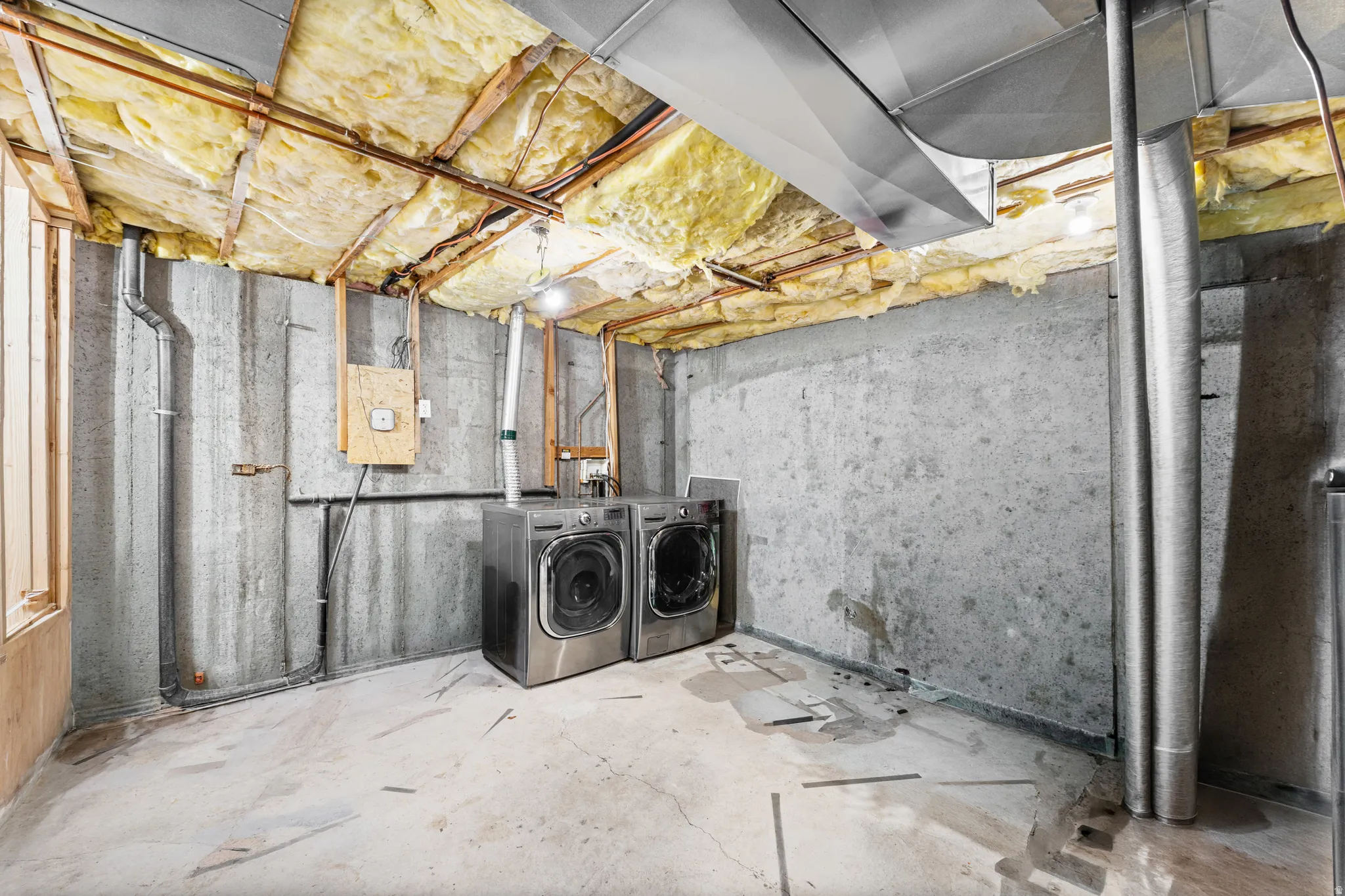 Unfinished basement with concrete slab flooring and exposed insulation