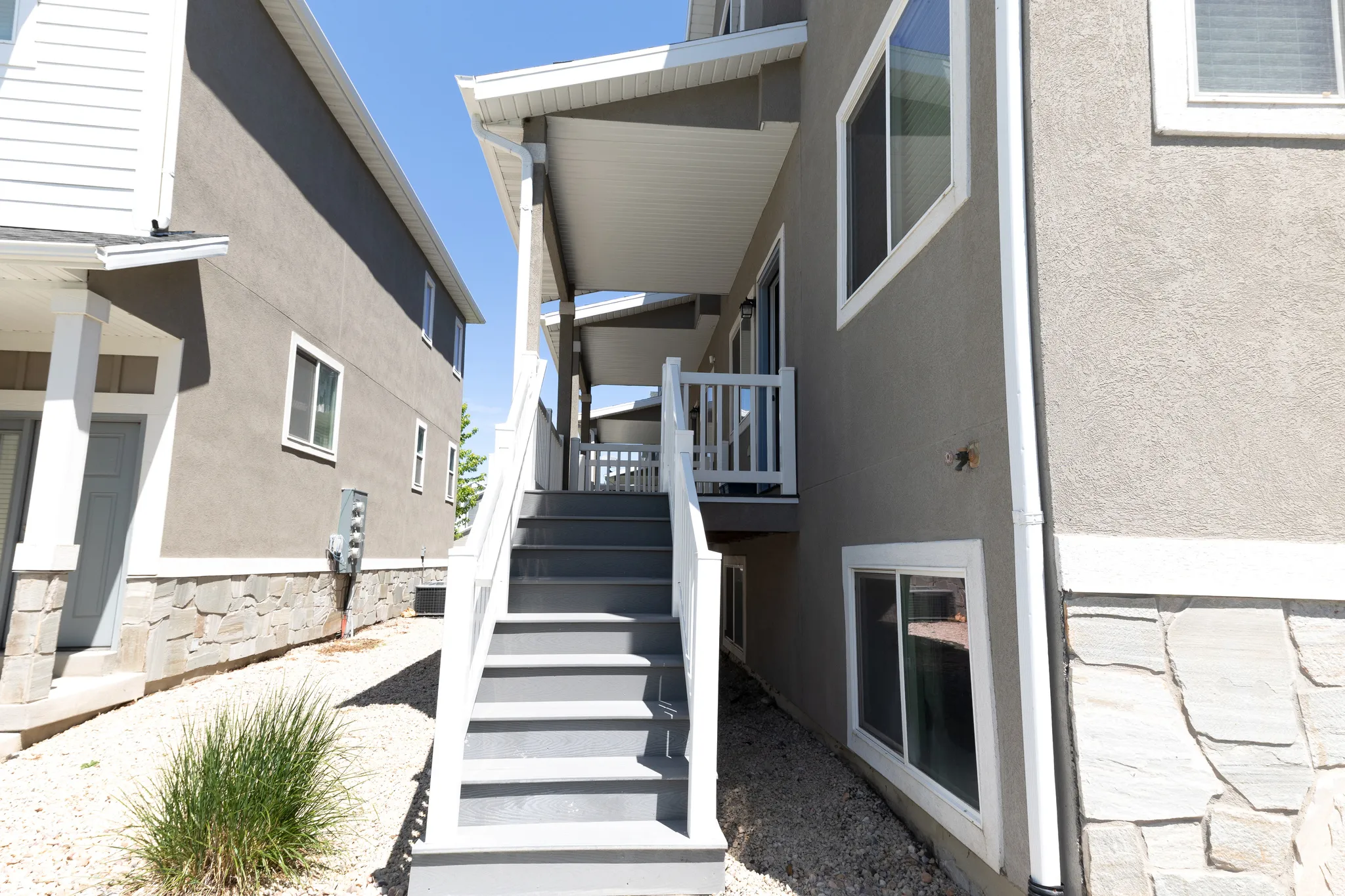 Covered exterior staircase with white railings, leading to an upper-level patio