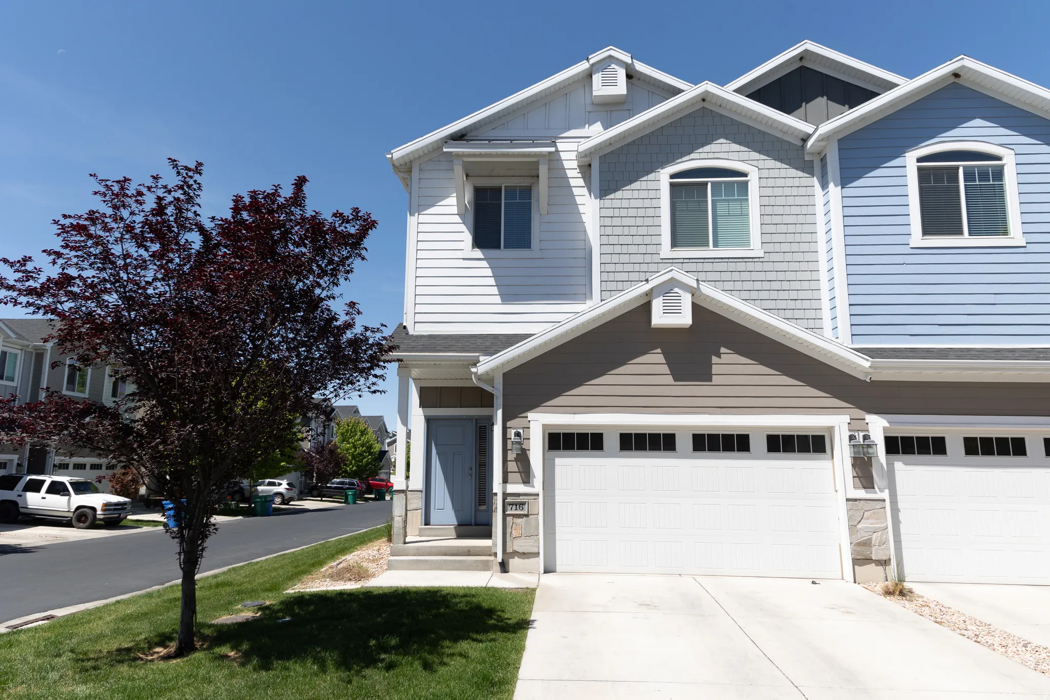 Multi-level townhouse exterior featuring a two-car garage, light blue entry door, and a combination of horizontal siding and shake shingles