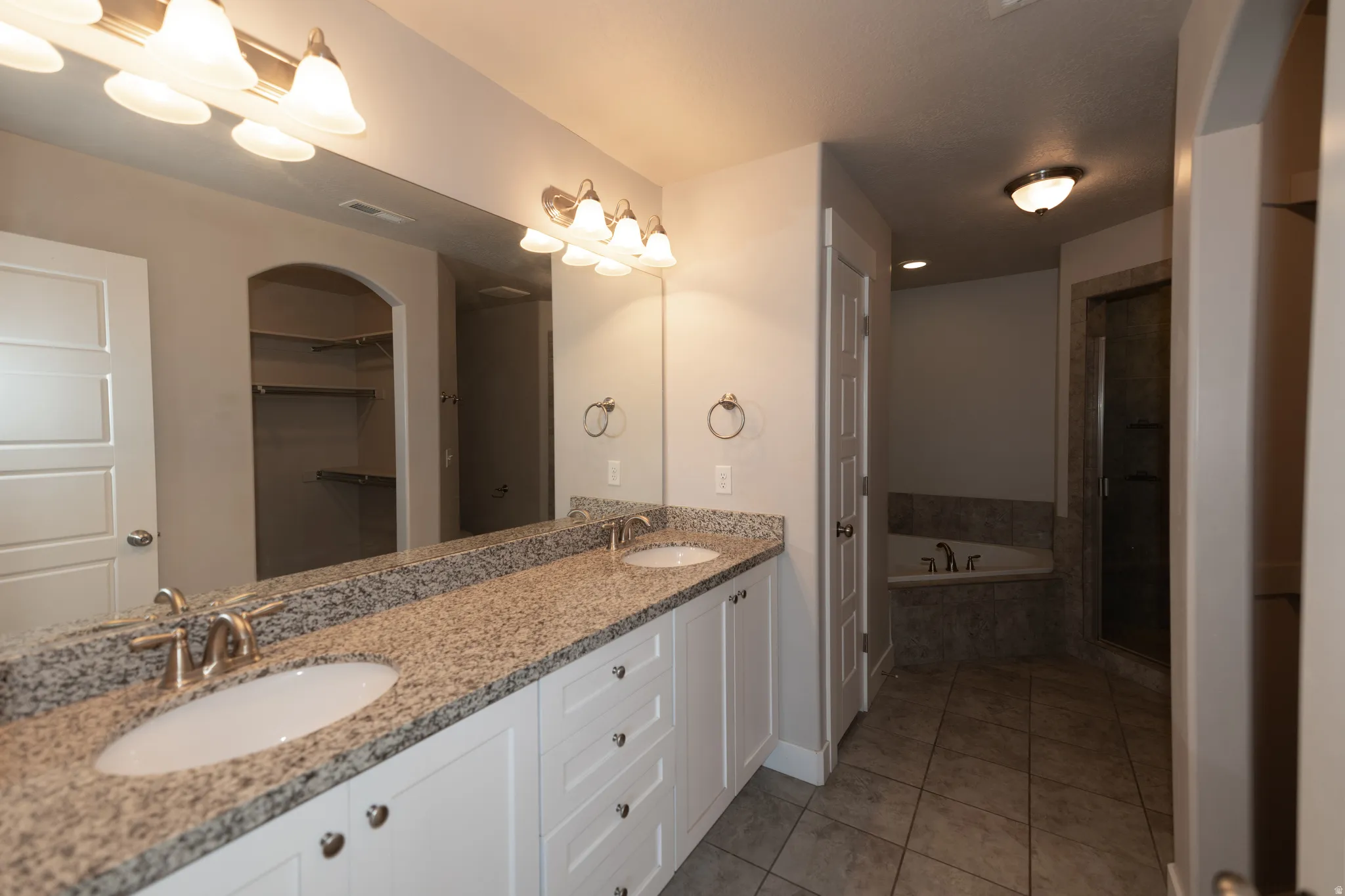 Dual vanity featuring a speckled countertop, undermount sinks, and brushed nickel faucets