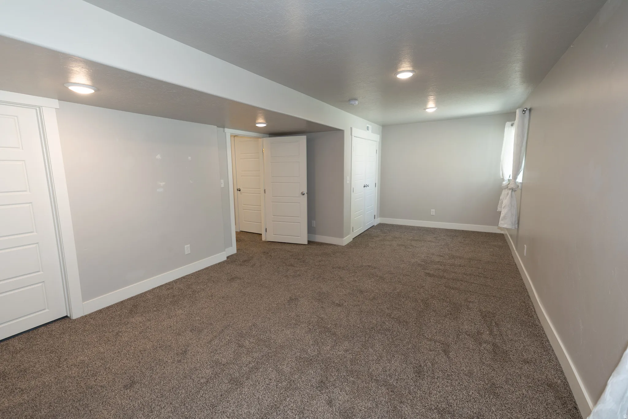Spacious room featuring neutral carpeting, light gray wall paint, and white trim