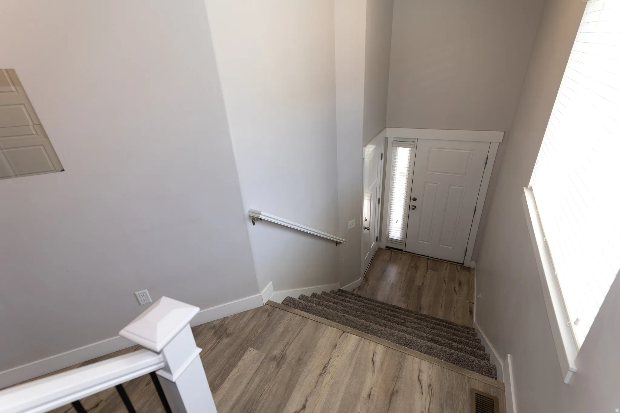 Entryway with a solid panel door and vertical window pane, featuring wood-finish flooring