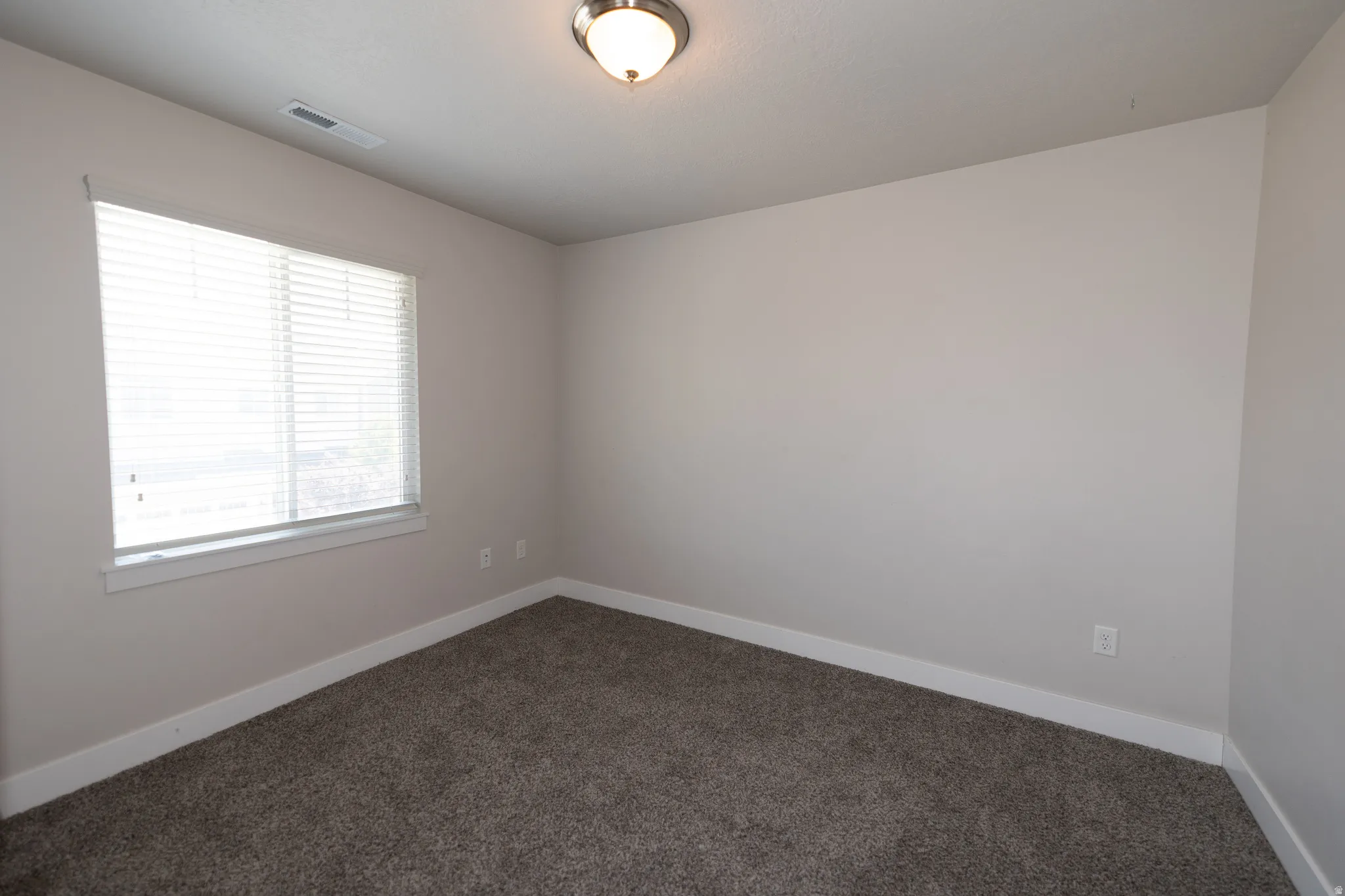 Room featuring neutral-toned walls, white trim, and textured gray carpeting