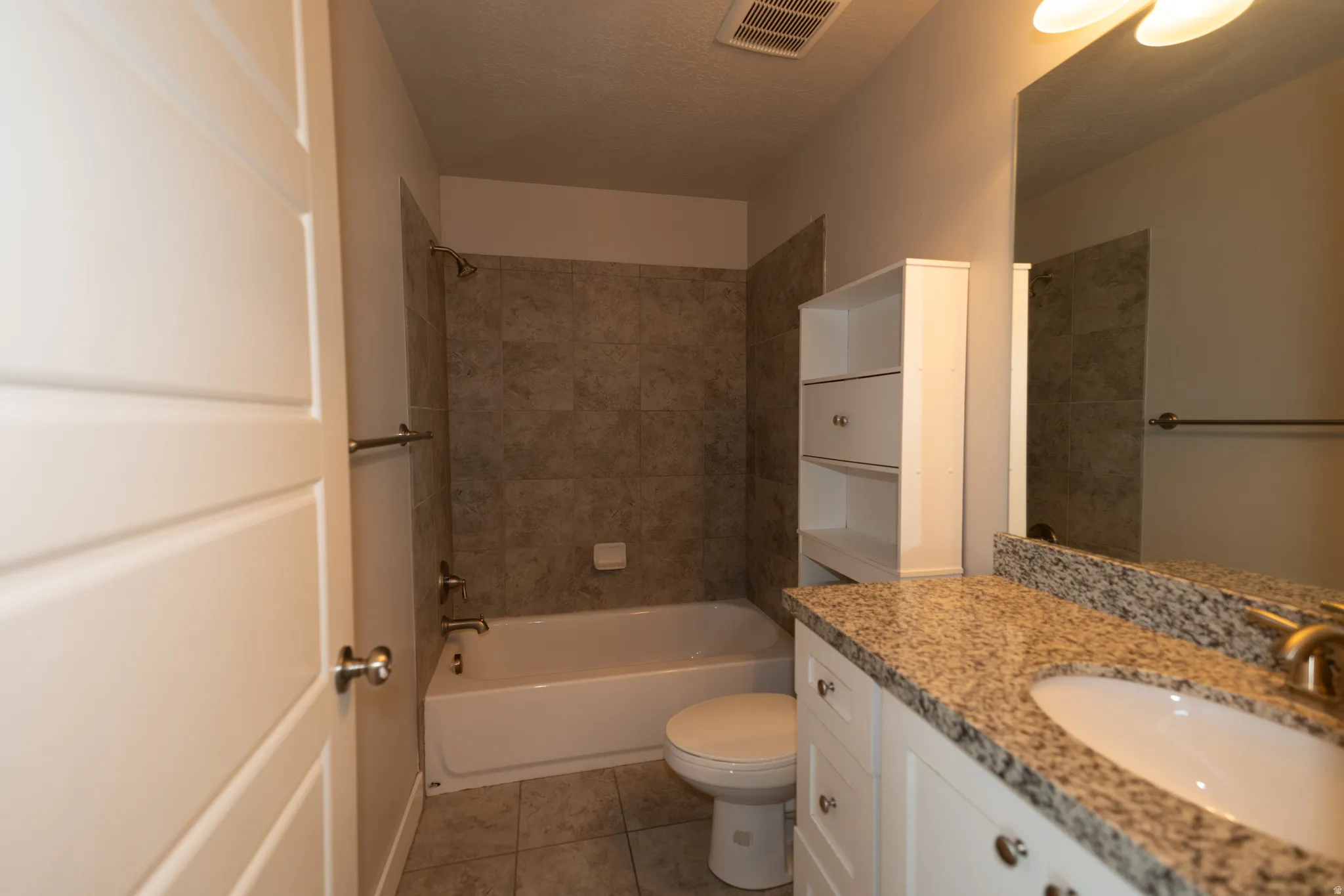 Bathroom featuring a white vanity with a granite-style countertop, undermount sink, and brushed nickel faucet