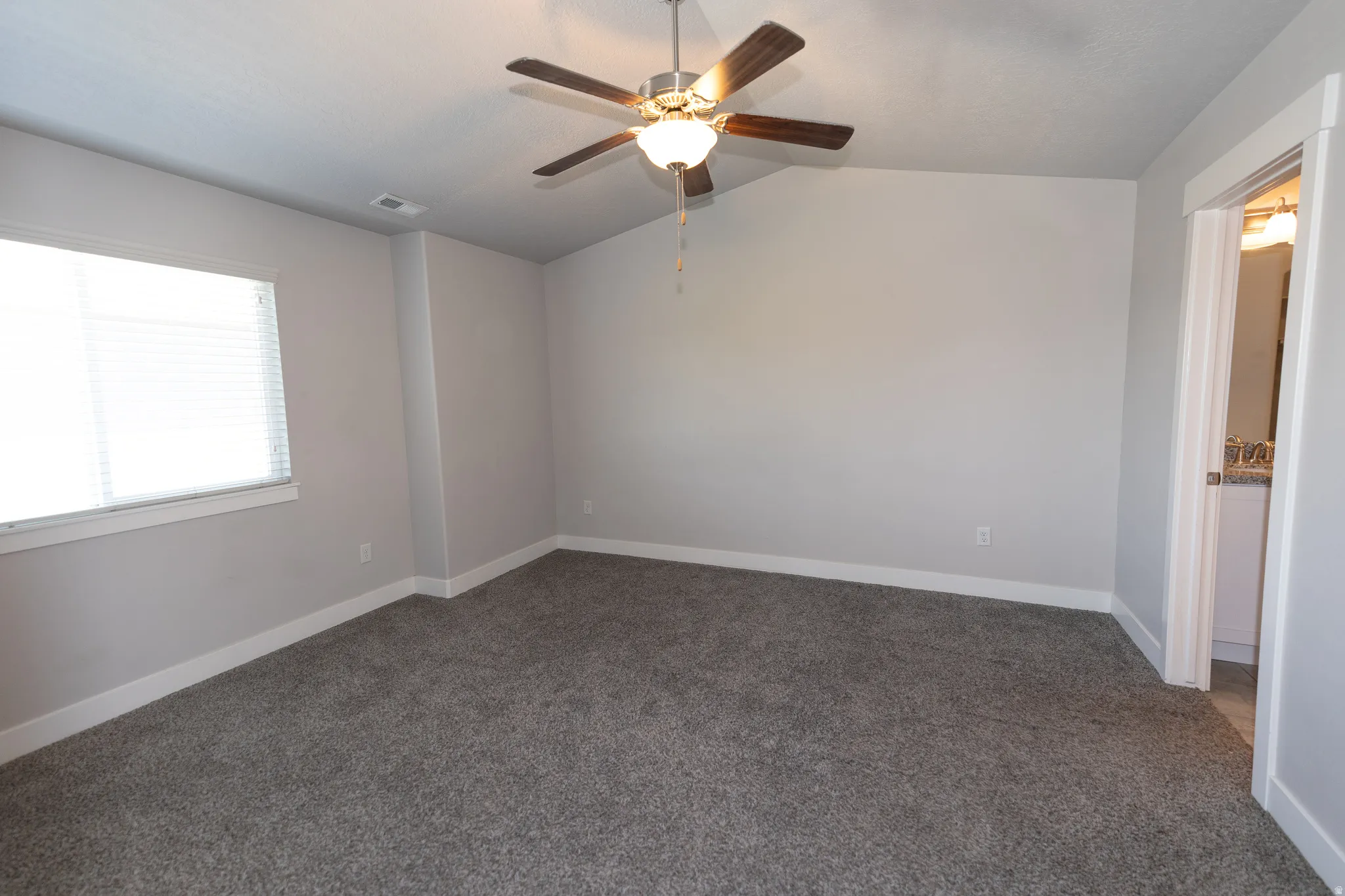Spacious room featuring neutral carpeting, light gray wall paint, and white trim