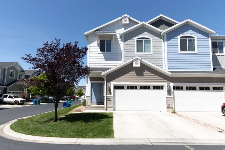 Contemporary townhome exterior featuring multi-toned siding, a covered entryway, and an attached two-car garage