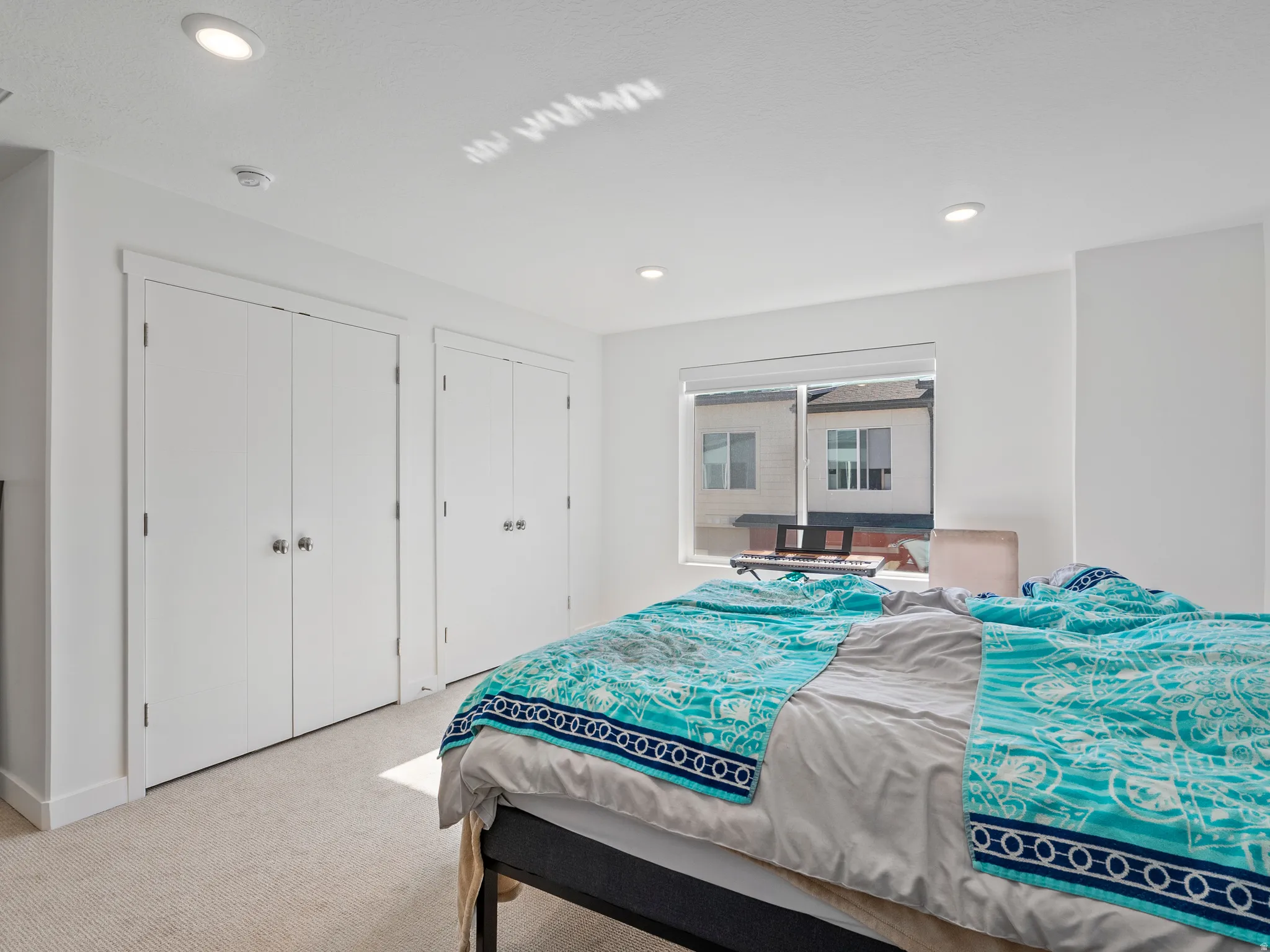 Bedroom featuring recessed lighting, light-toned carpeting, two sets of bi-fold closet doors