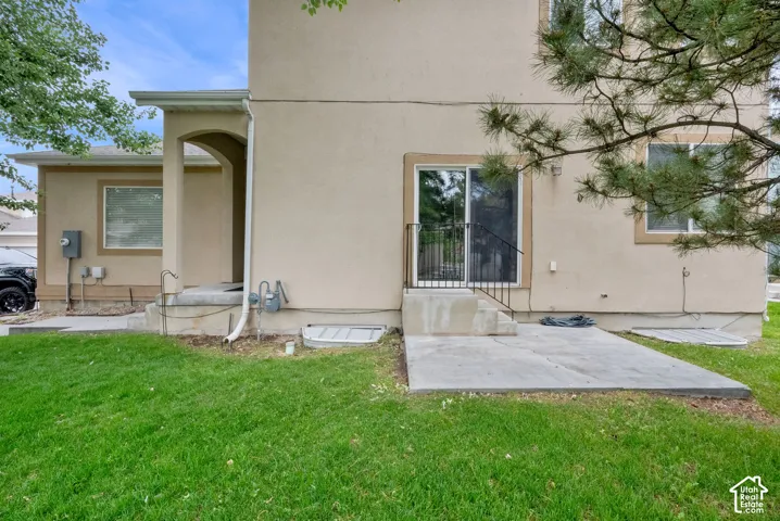 Expansive green lawn bordering a concrete patio with steps leading to a sliding glass door entry
