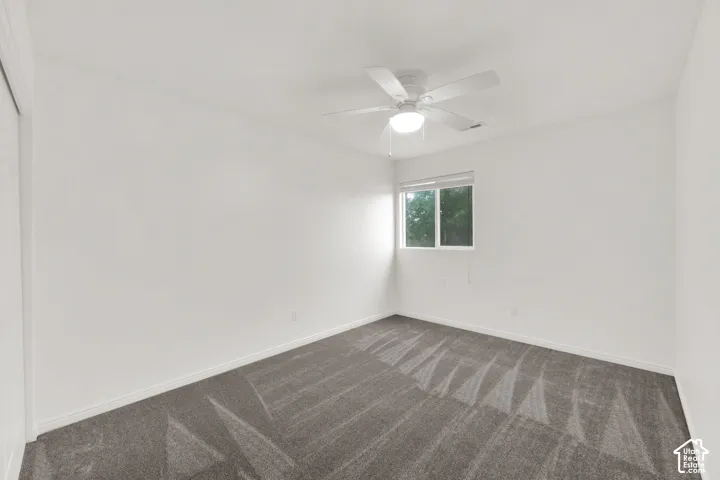 Room featuring a ceiling fan with integrated lighting, a window, and gray patterned carpeting