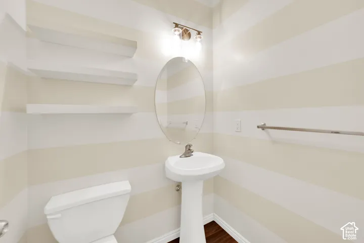 Pedestal sink vanity with an oval mirror and overhead lighting