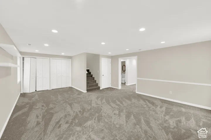 Spacious room featuring neutral carpeting, recessed lighting, and light-toned walls with chair rail molding