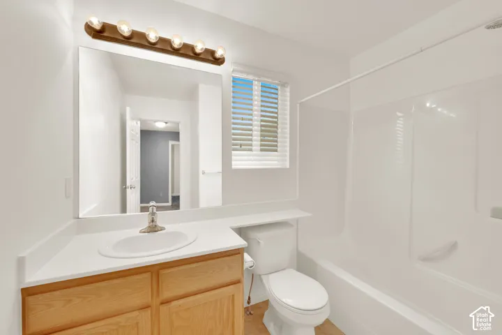 Bathroom featuring a wood-finish vanity with an integrated sink, a white countertop, and a large wall-mounted mirror