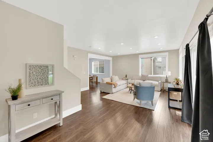Spacious living area featuring rich wood-finish flooring, recessed lighting, and ample natural light from multiple windows