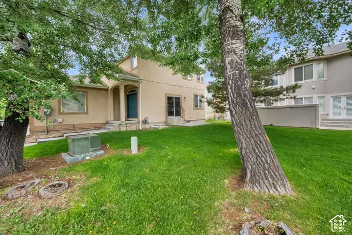 Lush green lawn with mature trees and a stucco exterior