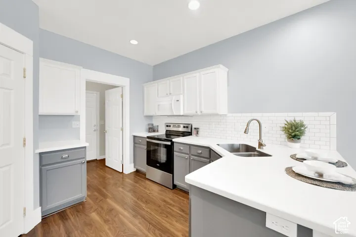 Kitchen featuring two-tone cabinetry with white upper and gray lower cabinets, white countertops, and wood-finish flooring