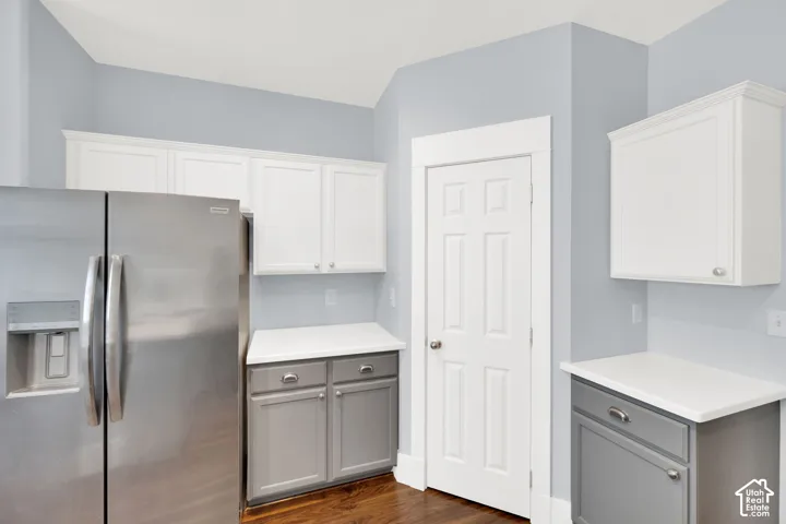 Kitchen featuring stainless steel refrigerator, white upper cabinetry, gray lower cabinetry, white countertops, and wood-finish flooring