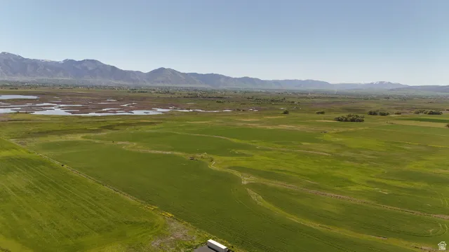 Expansive green fields with distant mountains and a large body of water