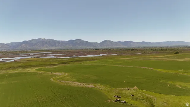 Expansive green fields with distant mountains and a body of water