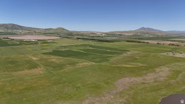Expansive land parcel featuring open fields and distant mountain ranges under a clear sky