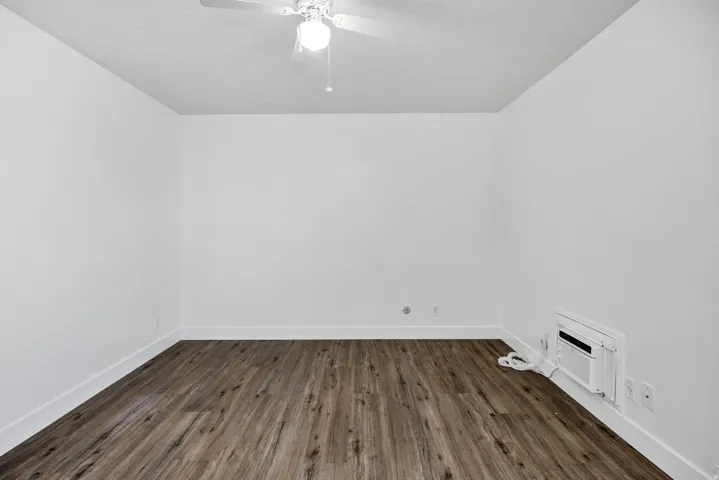 Room featuring wood-finish flooring, white baseboards, and a white ceiling fan with integrated lighting