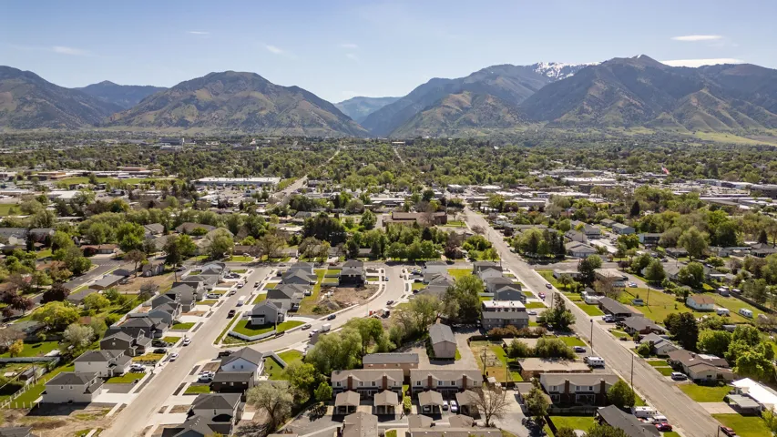 Residential neighborhood featuring multiple streets, mature trees, and a distant mountain range with snow-capped peaks