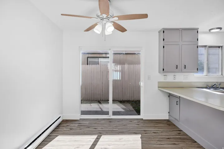 Interior space featuring wood-finish flooring, white walls, and a ceiling fan with light fixture