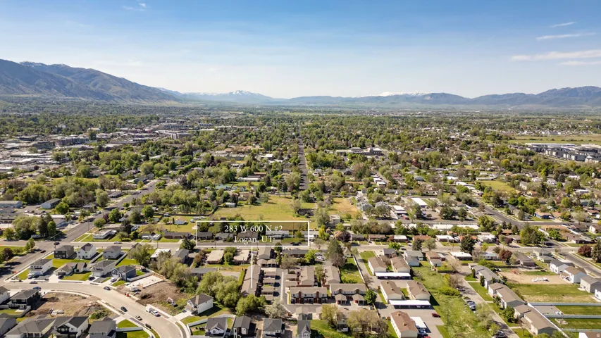 Aerial perspective showcasing a residential area with mature trees and mountain ranges in the background