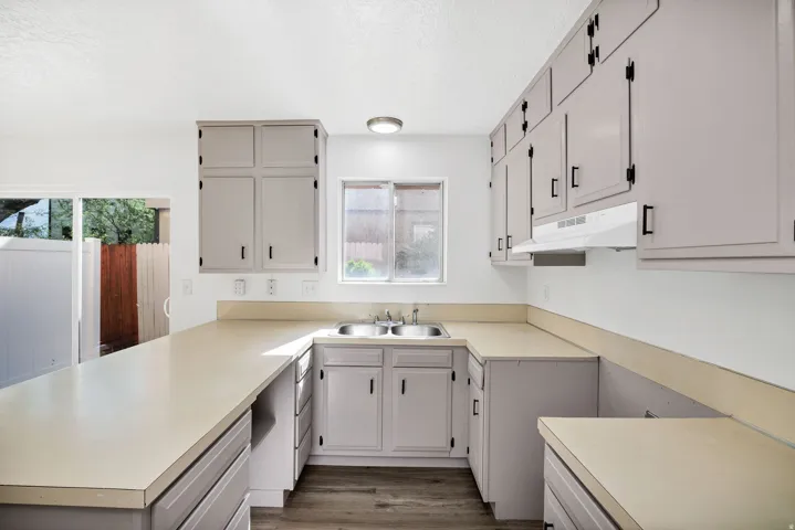 U-shaped kitchen featuring light gray cabinetry, laminate countertops, and wood-finish flooring