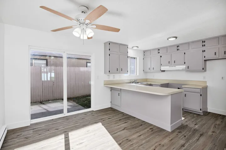 Kitchen featuring extensive grey cabinetry, light-toned countertops, and wood-finish flooring