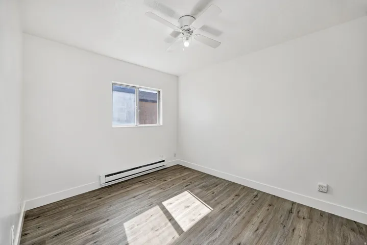 Room featuring wood-finish flooring, white baseboards, and a window with white trim