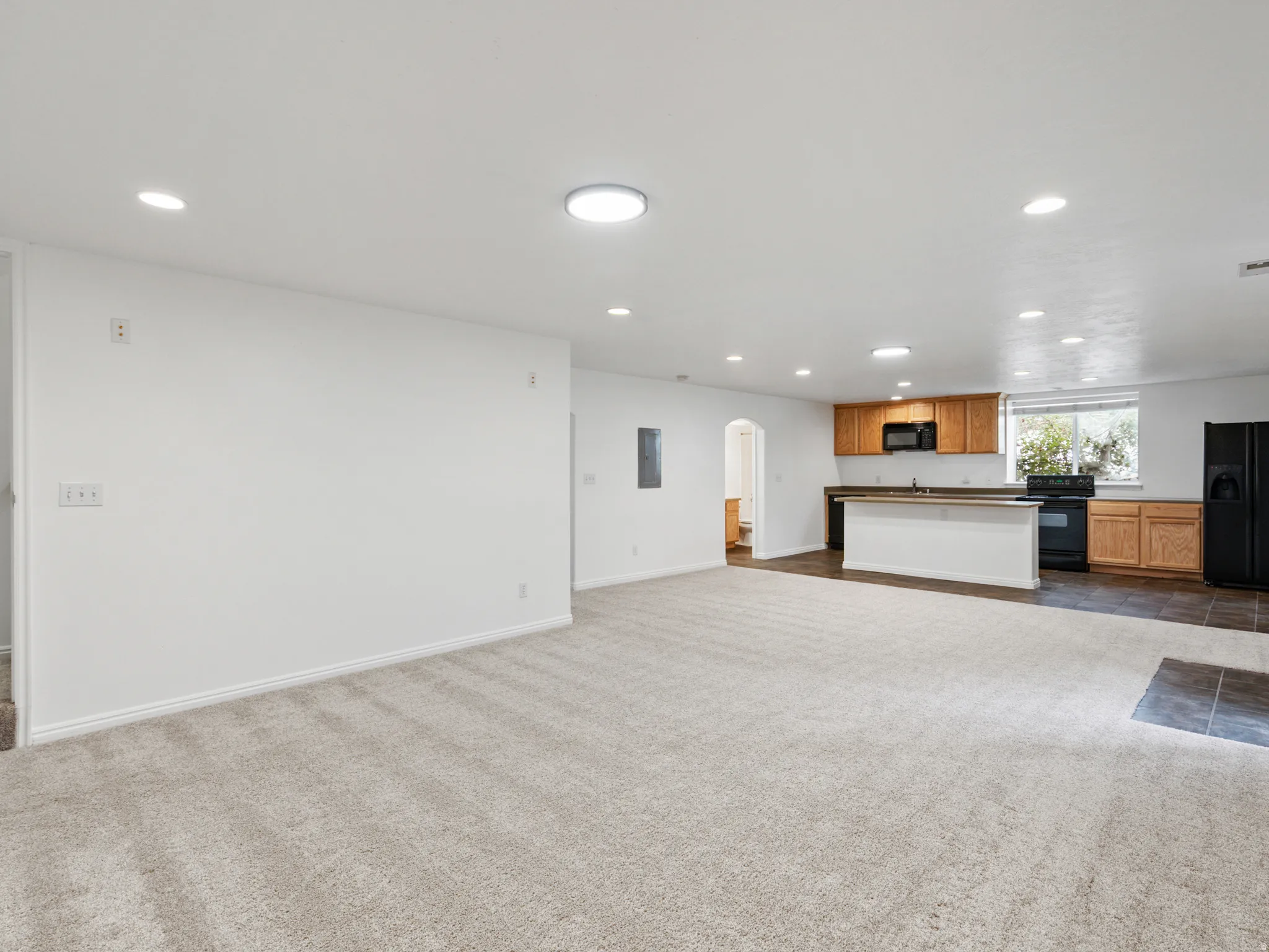 Open-concept living area featuring light-toned carpeting and recessed lighting