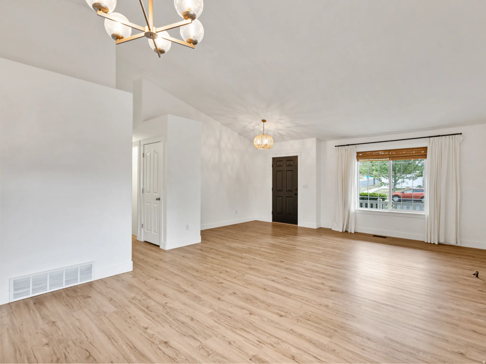 Expansive room featuring wood-finish flooring and vaulted ceilings