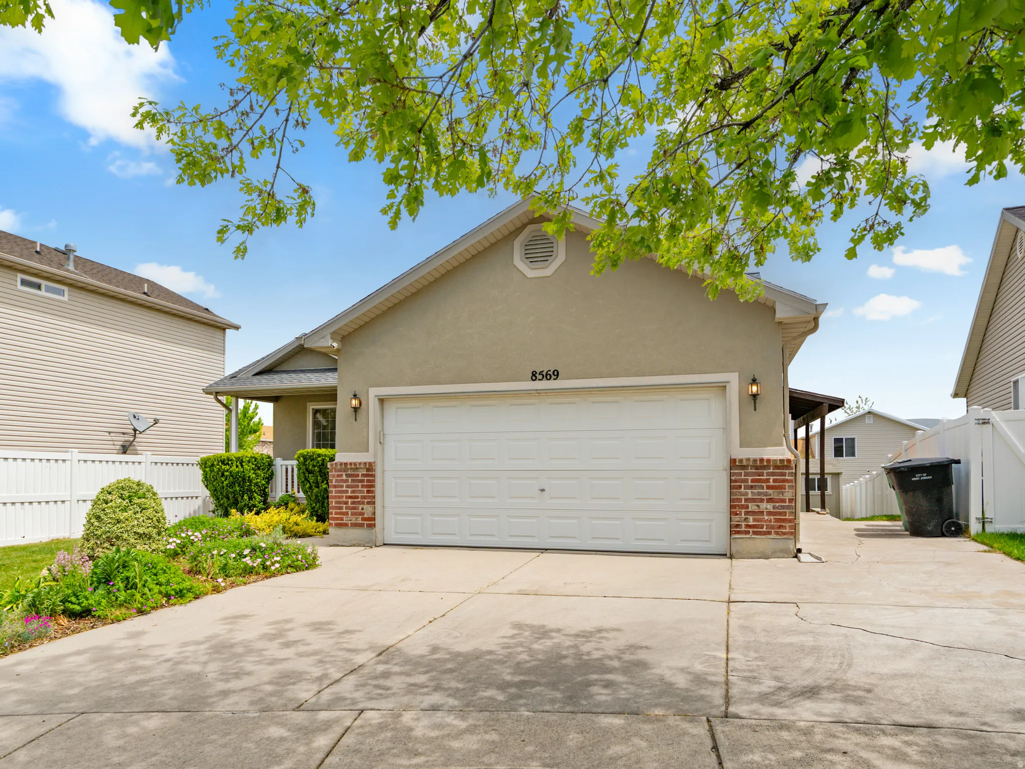 Stucco and brick facade featuring an integrated garage, covered entry, and concrete driveway