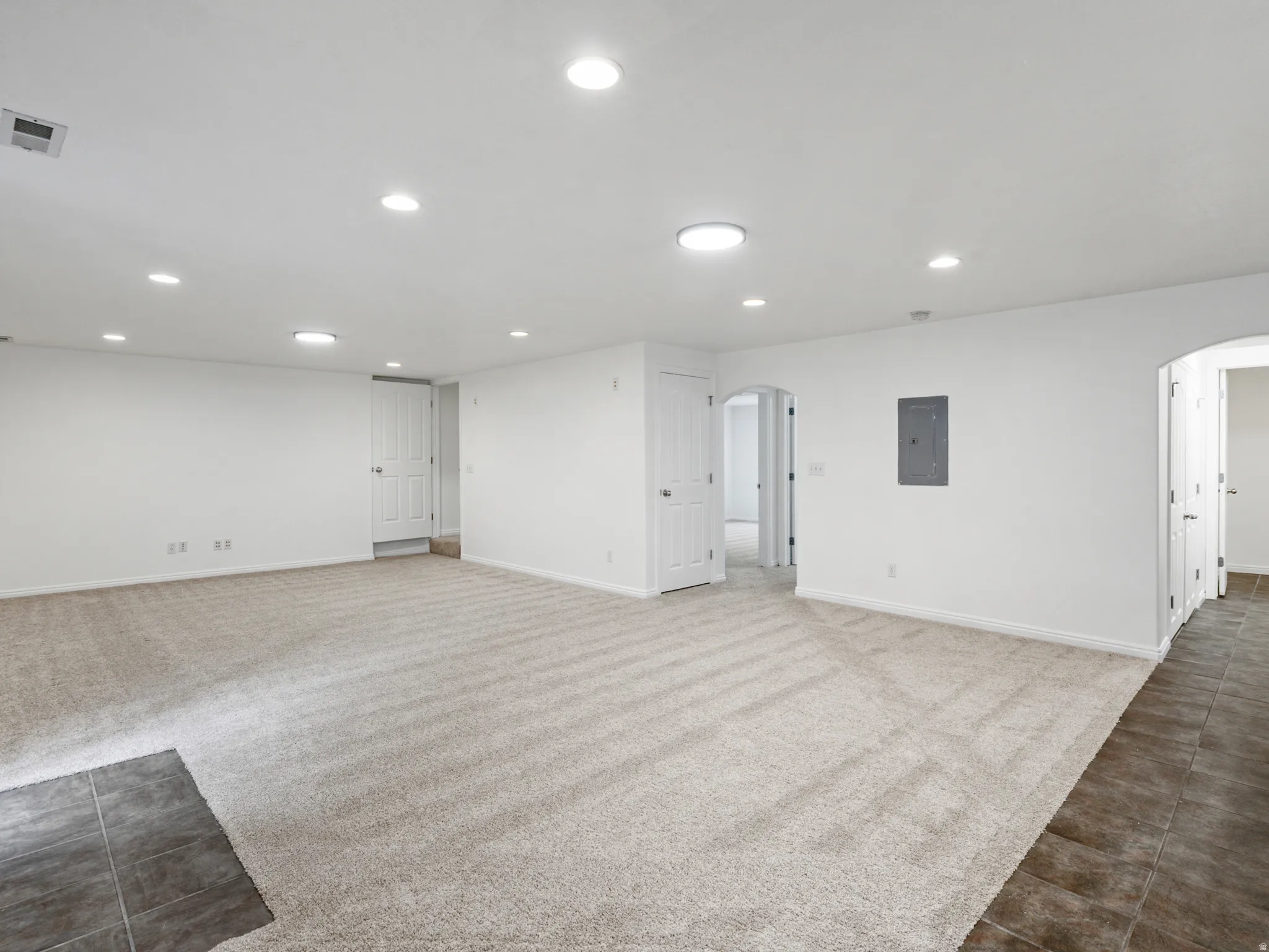 Spacious room featuring light-toned carpeting and recessed lighting
