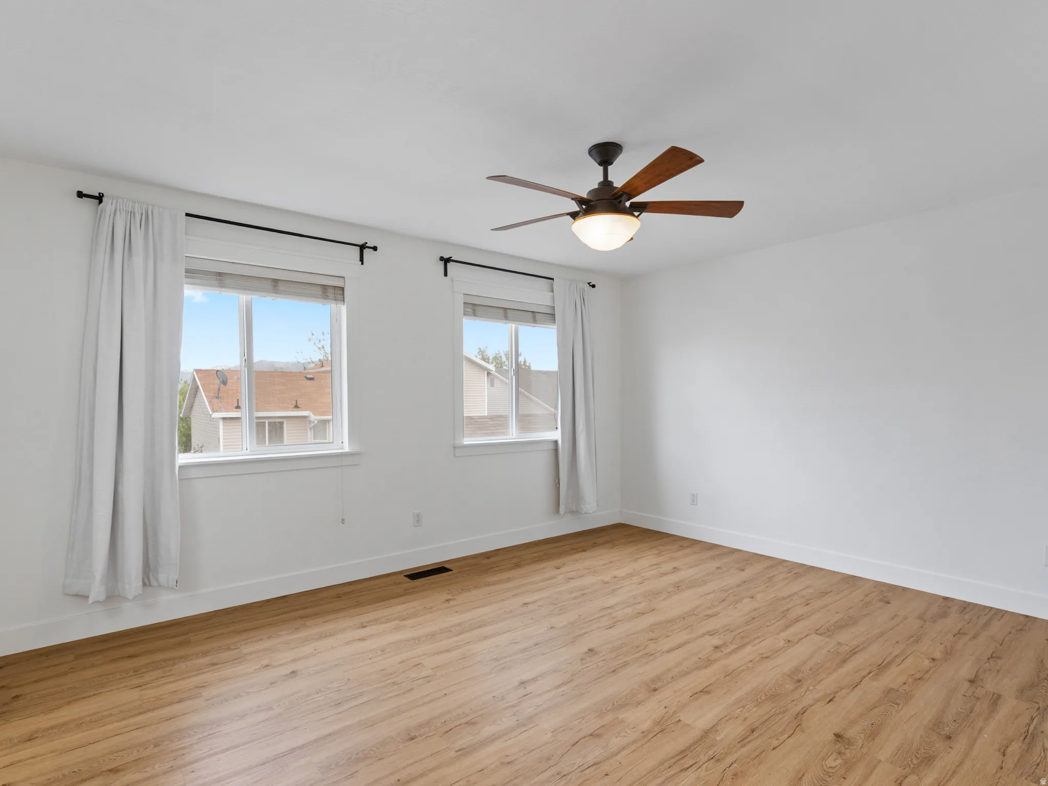 Bright interior space featuring wood-finish flooring, white walls, and a ceiling fan with integrated lighting