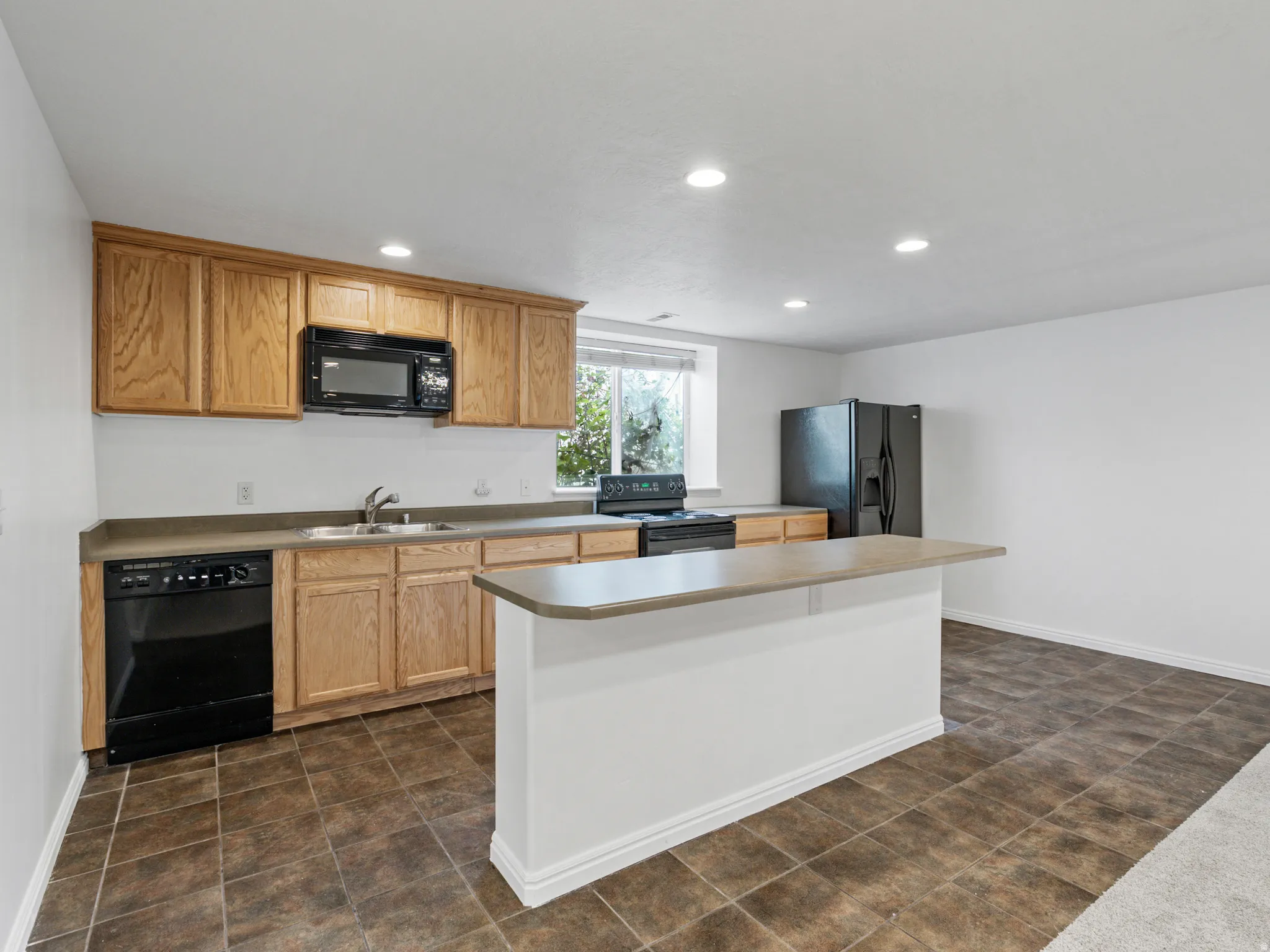Kitchen featuring wood cabinetry, dark countertops, and a central island with a breakfast bar