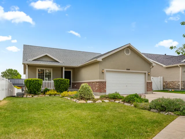 Ranch-style residence featuring a combination of stucco and brick siding, a white garage door, and a covered porch entry