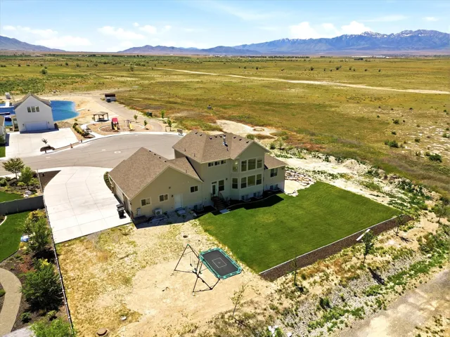Expansive backyard featuring a manicured lawn, established landscaping, and a concrete patio