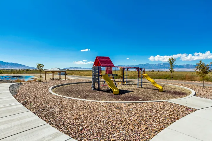 Recreational playground featuring two yellow slides, a swing set, and a red-roofed playhouse structure