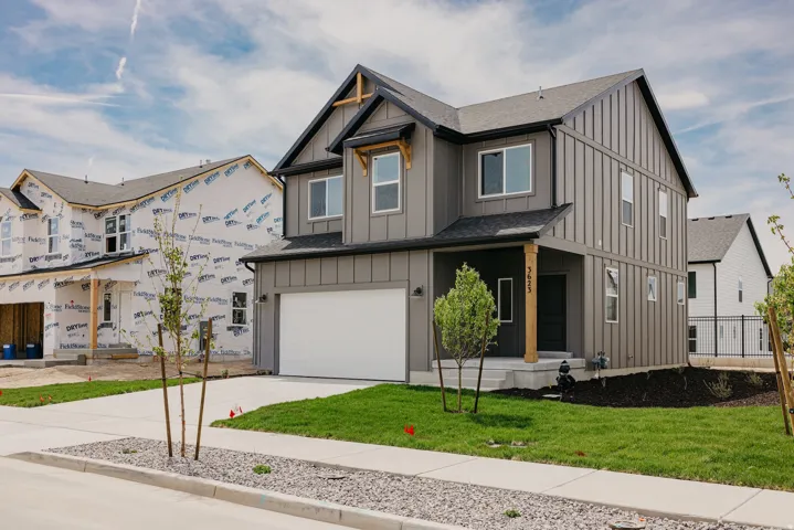 Two-story residence featuring vertical board and batten siding, a single-car garage, covered porch entry with a timber post, and a shingled roof