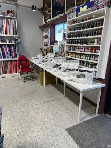 Open-concept retail space featuring extensive built-in shelving, durable light-tone flooring, and multiple work surfaces